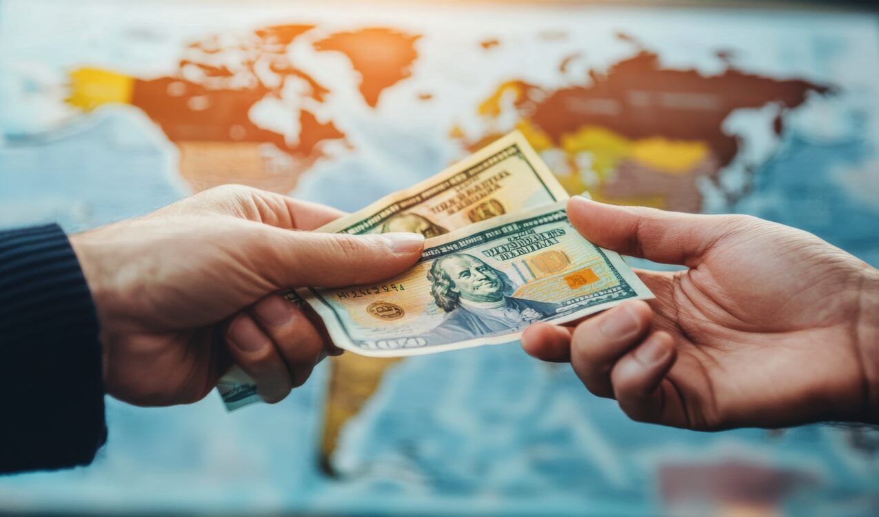 Hands exchanging cash in front of a world map, representing foreigner loan eligibility in Singapore, cross-border financial support, and legal lending guidance for expatriates and overseas workers.