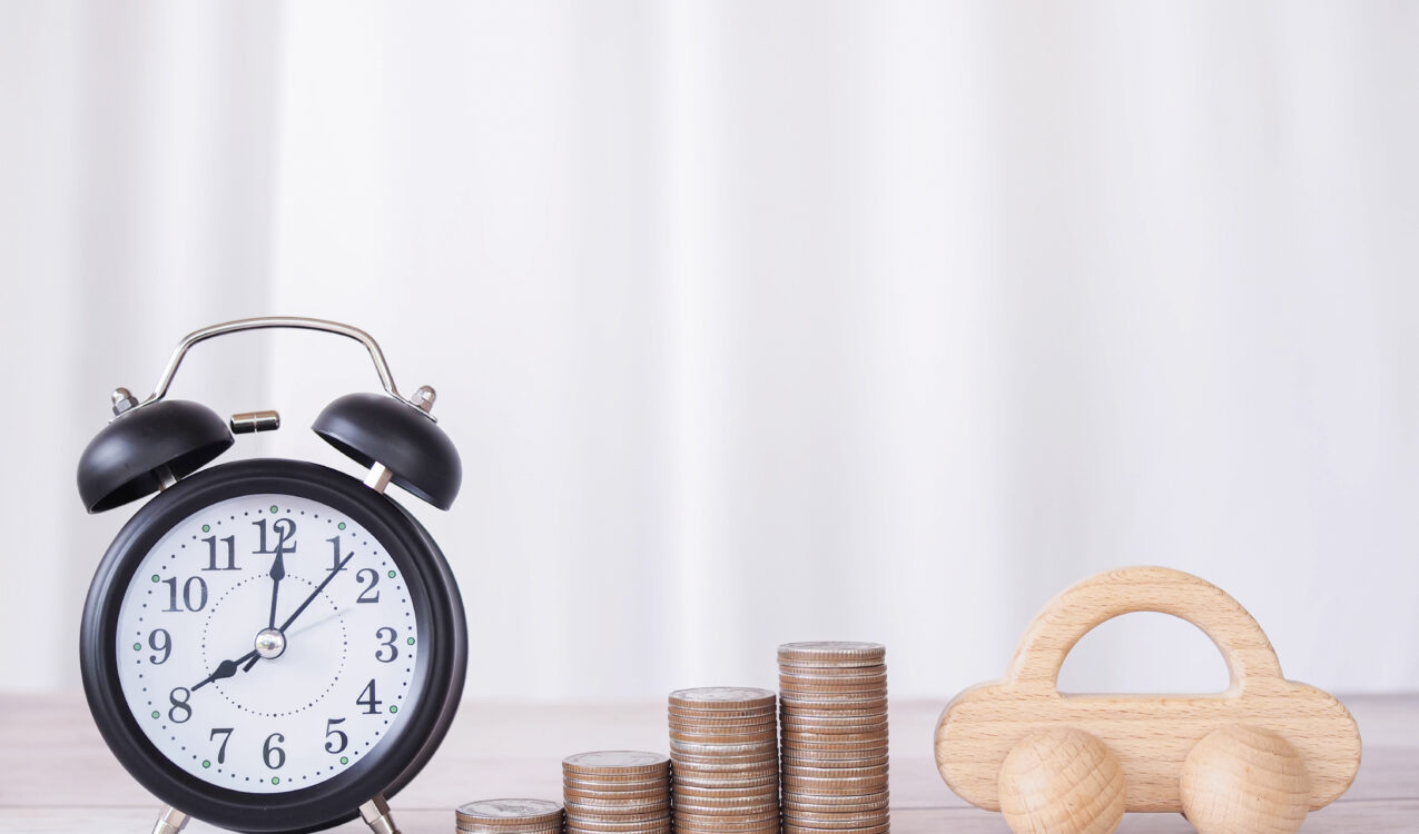 An alarm clock, stacked coins, and a toy car placed together to represent payday loans, repayment timelines, and financial responsibilities—highlighting how Khalon & Gill helps borrowers understand whether payday loans are legal in Singapore.