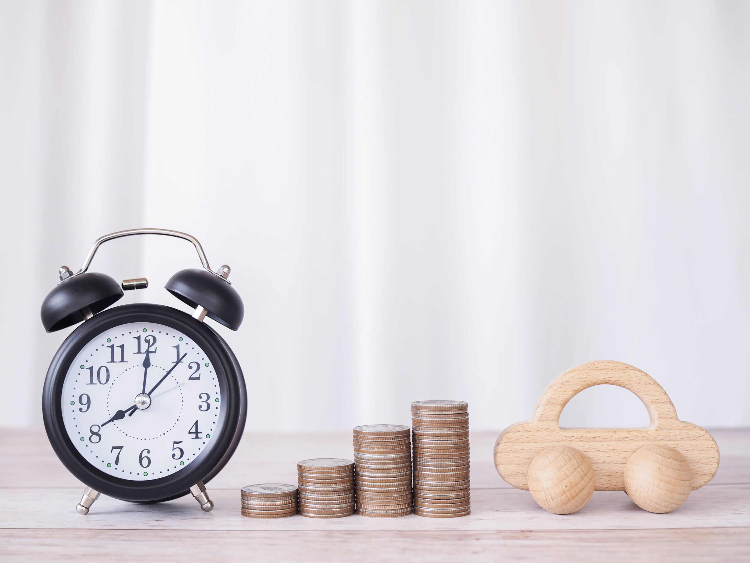 An alarm clock, stacked coins, and a toy car placed together to represent payday loans, repayment timelines, and financial responsibilities—highlighting how Khalon & Gill helps borrowers understand whether payday loans are legal in Singapore.