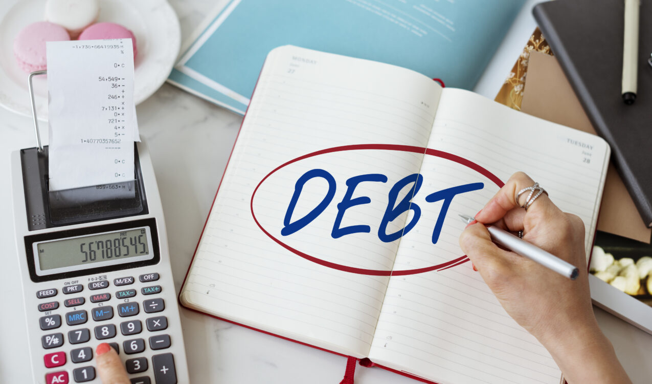 Person planning debt repayments in a notebook beside a calculator to avoid debt traps when taking a cash loan in Singapore.
