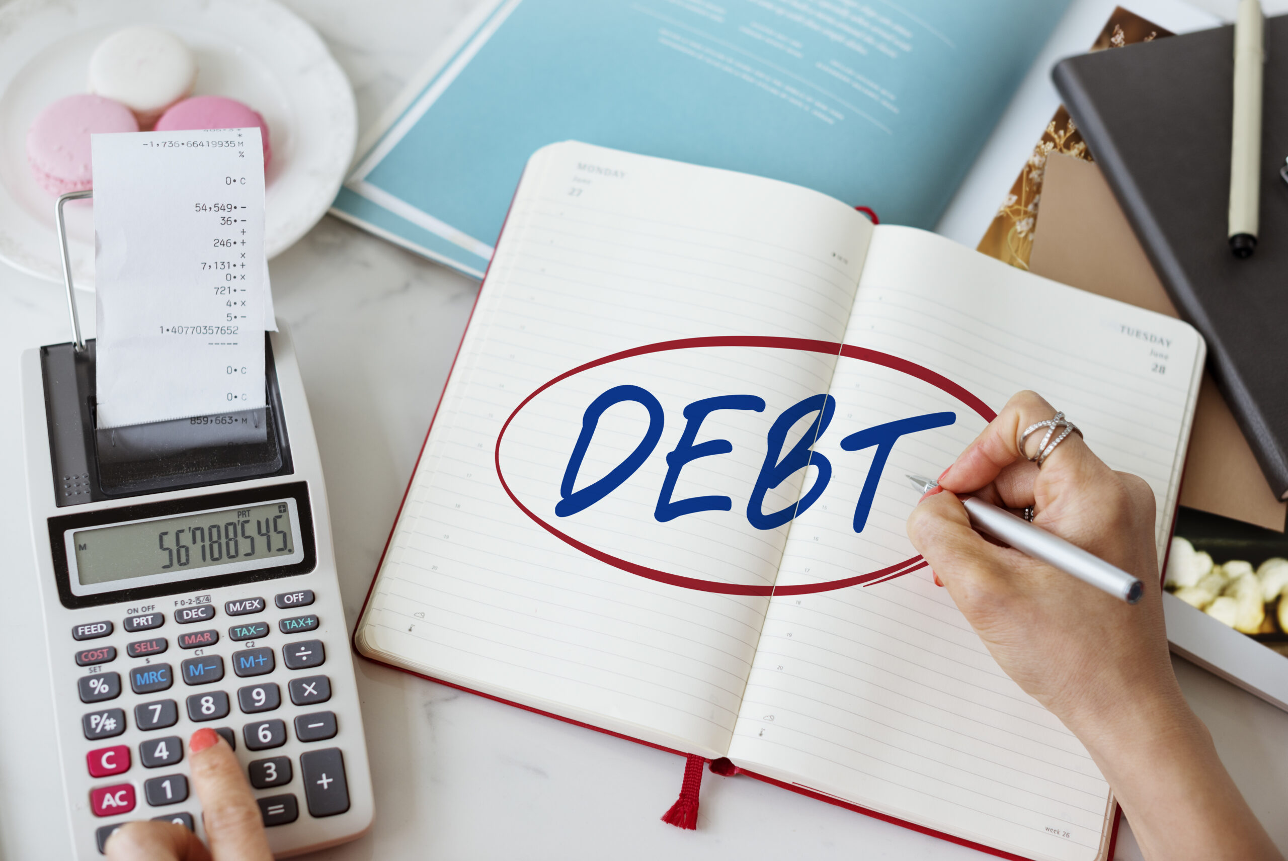 Person planning debt repayments in a notebook beside a calculator to avoid debt traps when taking a cash loan in Singapore.