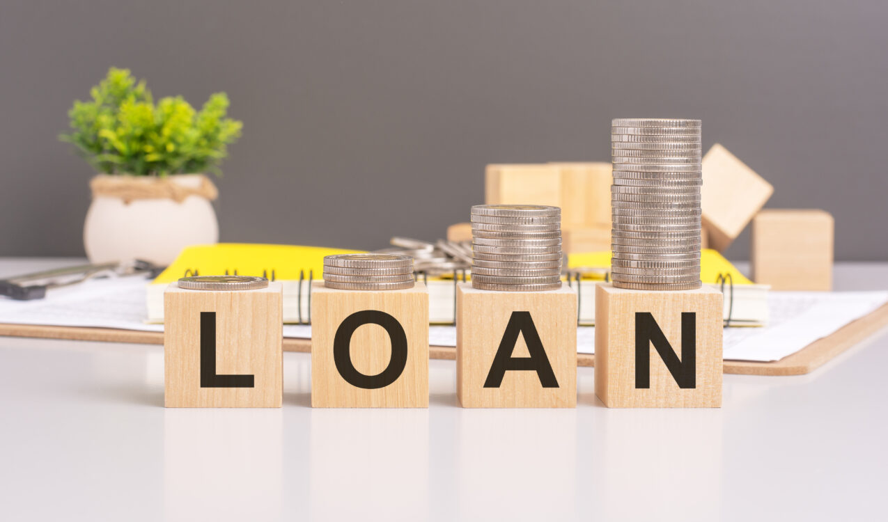 Wooden blocks spelling 'LOAN' with stacks of coins increasing in height, representing personal loans, borrowing, and financial planning in Singapore.