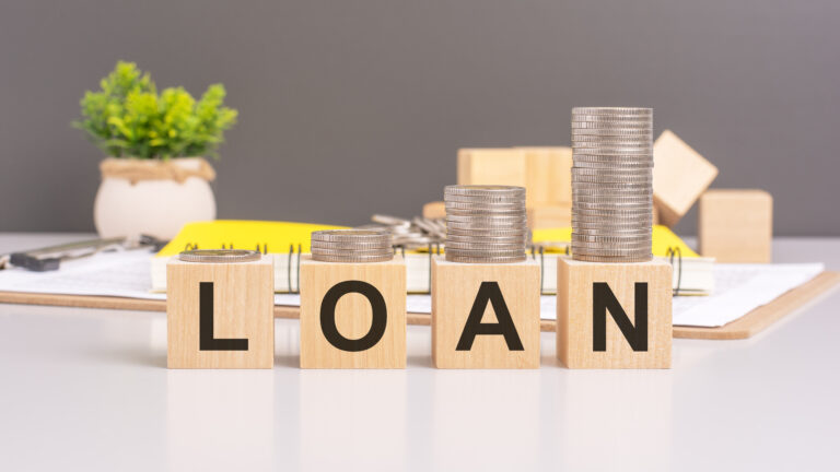 Wooden blocks spelling 'LOAN' with stacks of coins increasing in height, representing personal loans, borrowing, and financial planning in Singapore.