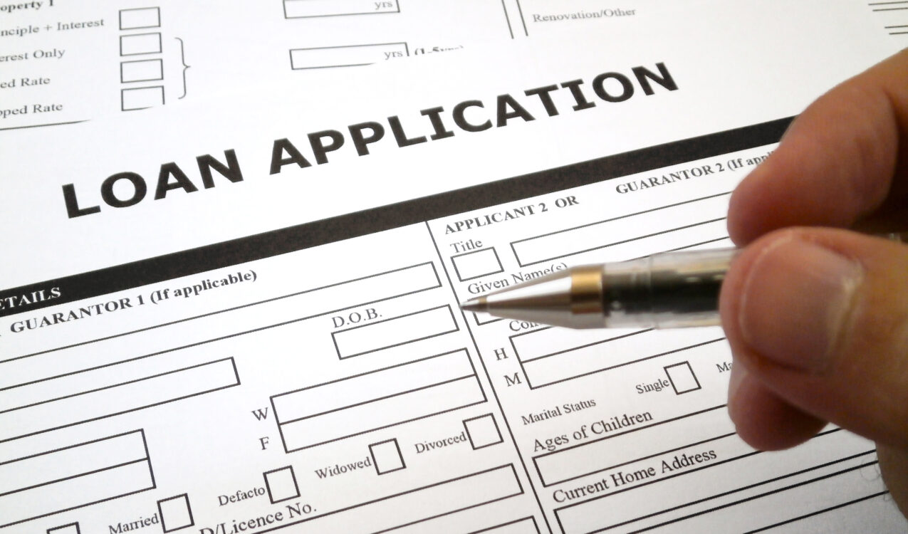 Person filling out a payday loan application form with a pen to apply for short-term cash assistance.