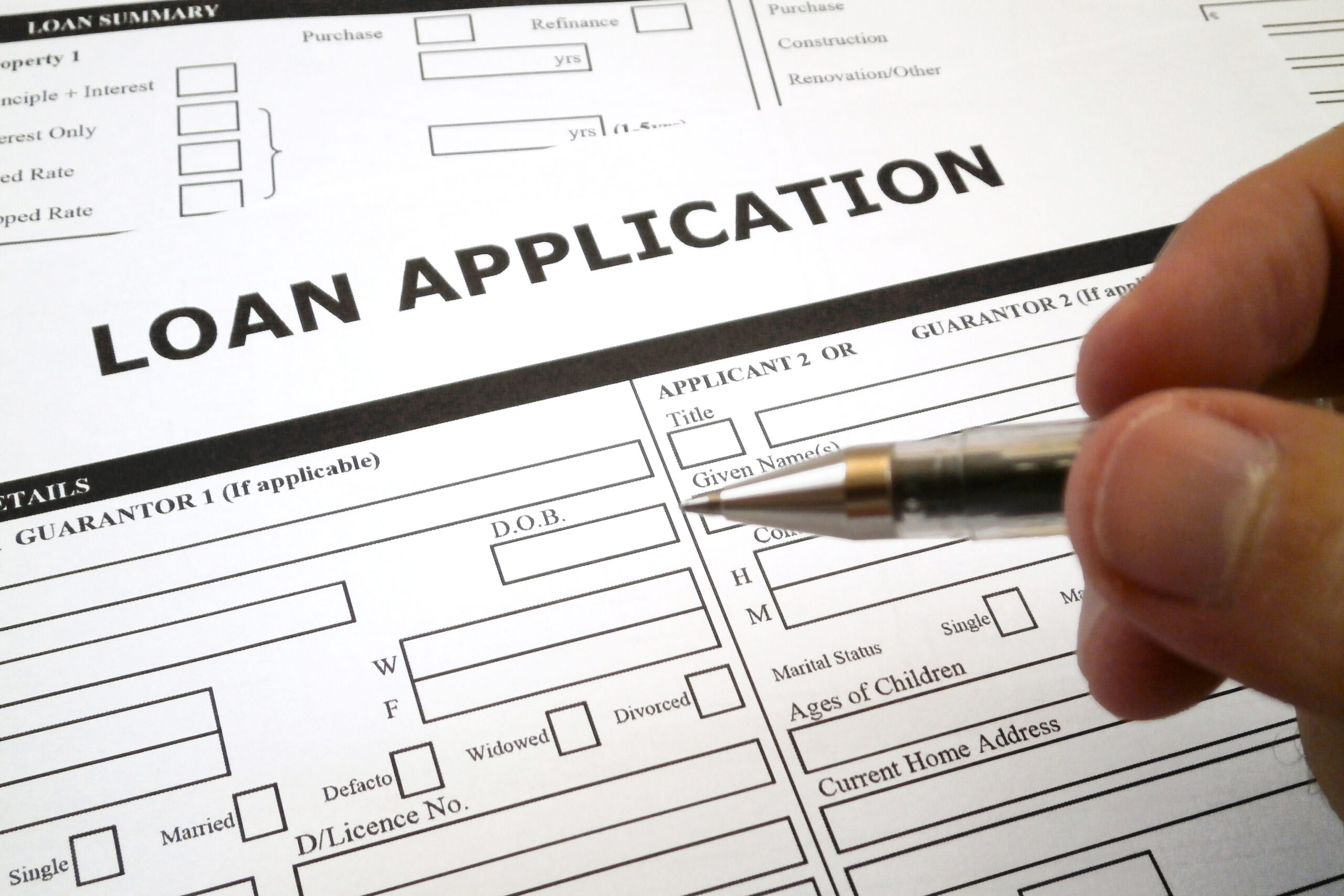 Person filling out a payday loan application form with a pen to apply for short-term cash assistance.