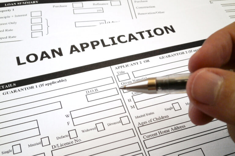 Person filling out a loan application form with a pen, representing the loan application process and financing services for EP holders by Khalon & Gill.
